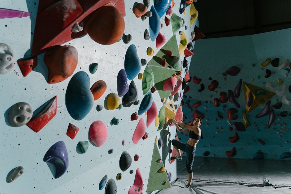 Woman bouldering on a colorful indoor climbing wall, wearing activewear.